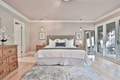 a bedroom with a bed, dressers and large glass doors leading to an outside patio