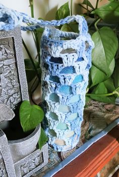 a crocheted vase sitting on top of a table next to a potted plant