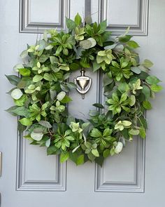 a wreath on the front door is adorned with green leaves and an old fashioned bell