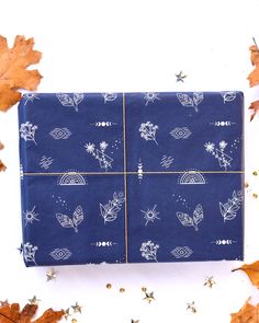 a blue wrapping paper with white leaves on it and gold glitters around the edges