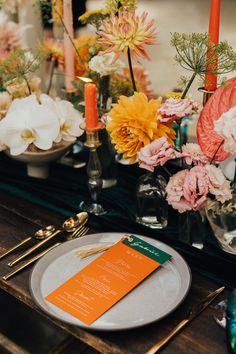 the table is set with flowers, candles and menu cards for guests to sign in