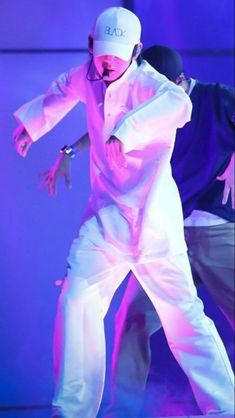 two men in white outfits are dancing on stage