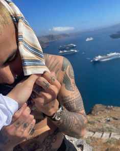 a man with tattoos covering his face next to the ocean