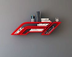 a red shelf with books and other items on it against a gray wall in an office setting