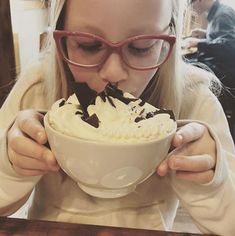 a girl eating ice cream with chocolate on top