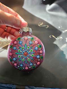 a hand holding a glass ornament on top of a table