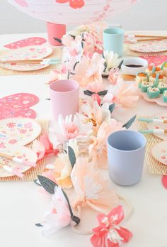 a table topped with plates and cups filled with flowers