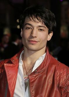 a man in a red leather jacket and white shirt is looking off to the side