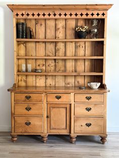 an old wooden bookcase with drawers and cupboards on the bottom, in front of a white wall