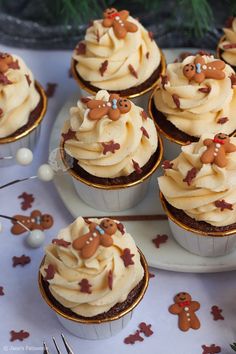 cupcakes with frosting and decorations are on a white plate next to silverware