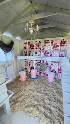 a room that has some pink buckets on the floor in front of it and a chandelier hanging from the ceiling