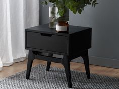 a black table with a potted plant on it and a white curtain in the background