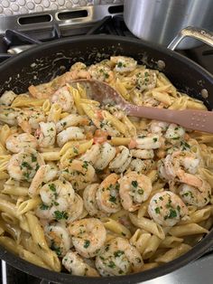 pasta with shrimp and parmesan cheese in a skillet on top of the stove