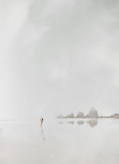 a person walking on the beach with an umbrella over their head and in the water