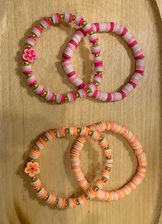 three bracelets on a wooden table next to a flower beaded bracelet and ring