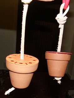 two clay pots with candles in them sitting on a table next to another potted plant