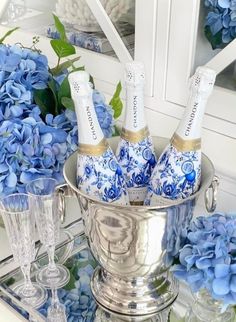 blue hydrangeas and champagne bottles in a silver ice bucket on a mirrored tray