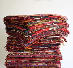 a stack of multicolored cloths sitting on top of each other in front of a white wall