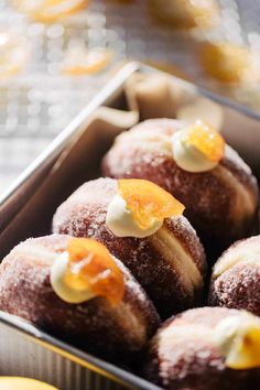 a box filled with donuts covered in powdered sugar and orange zesty toppings