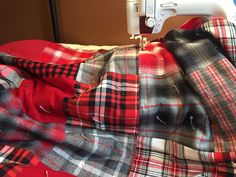 a red and black plaid blanket with a white sewing machine on the table next to it