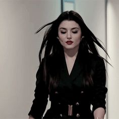 a woman with long hair walking down a hallway