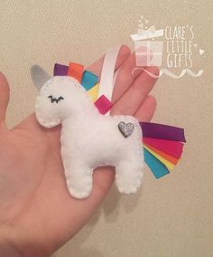 a hand holding a small white stuffed unicorn