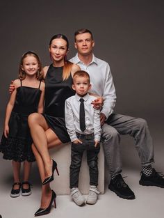 a family posing for a photo in black and white outfits with their little boy wearing a tie