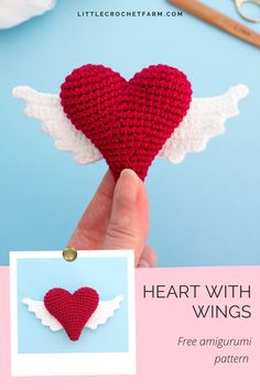 a crocheted heart with wings is being held up