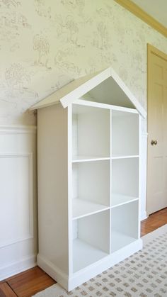 a white bookcase in the corner of a room next to a door and carpet