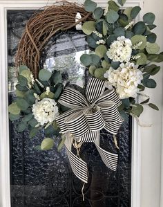 a wreath with white flowers and greenery on the front door