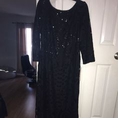 a black dress with sequins on it is hanging in front of a door