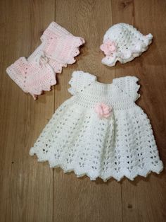 a crocheted baby dress and booties are on the floor