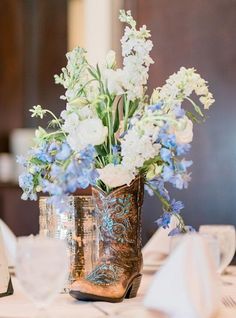 a cowboy boot with flowers in it sits on a table next to a place card holder