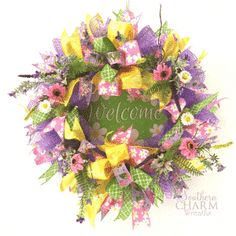 a welcome wreath with yellow and purple flowers on the front, hanging from a wall