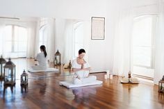 a woman is practicing yoga in the middle of a room with wood floors and windows