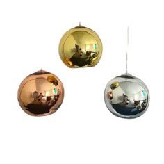 three mirrored balls hanging from the ceiling in front of a white wall and one has a reflection of people sitting at a table