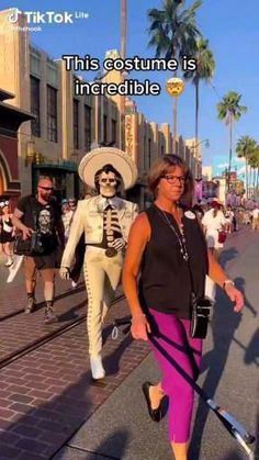 a woman walking down the street with a skeleton on her head and people in costume behind her