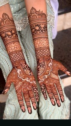 two hands with henna tattoos on them, one is showing off the intricate design