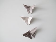 three origami butterflies are hanging on the wall, one is black and white