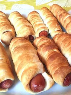 several hot dogs wrapped in bread are on a white plate and ready to be eaten