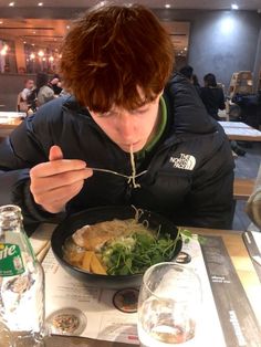 a young man eating food from a bowl on top of a table in a restaurant