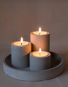 three lit candles sitting on top of a tray with two smaller ones in the middle