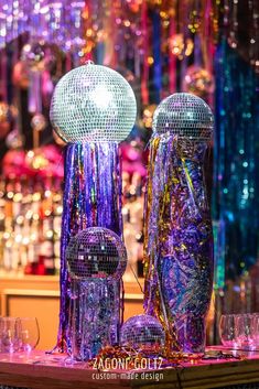 two disco balls and some wine glasses on a table in front of many other items