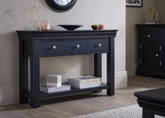 a black console table with two drawers and a clock on the wall above it in a living room