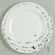 a white plate with birds on it and black trimmings around the rim, against a gray background