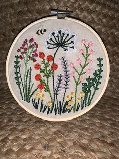 a close up of a embroidery on a piece of cloth with flowers and a bee