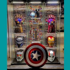 a display case filled with different types of avengers masks and lights on the wall behind it