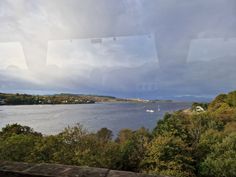 the view from inside a train looking out at water and trees in the foreground