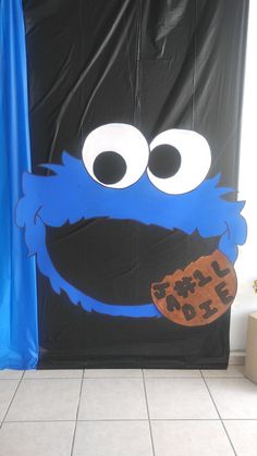 a door decorated to look like an cookie monster with eyes and mouth, standing in front of a blue curtain