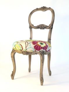 an antique chair with colorful fabric on it's seat and backrest, against a white background